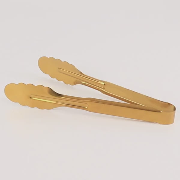 Gold metal serving tongs with scalloped edge for buffets and parties.