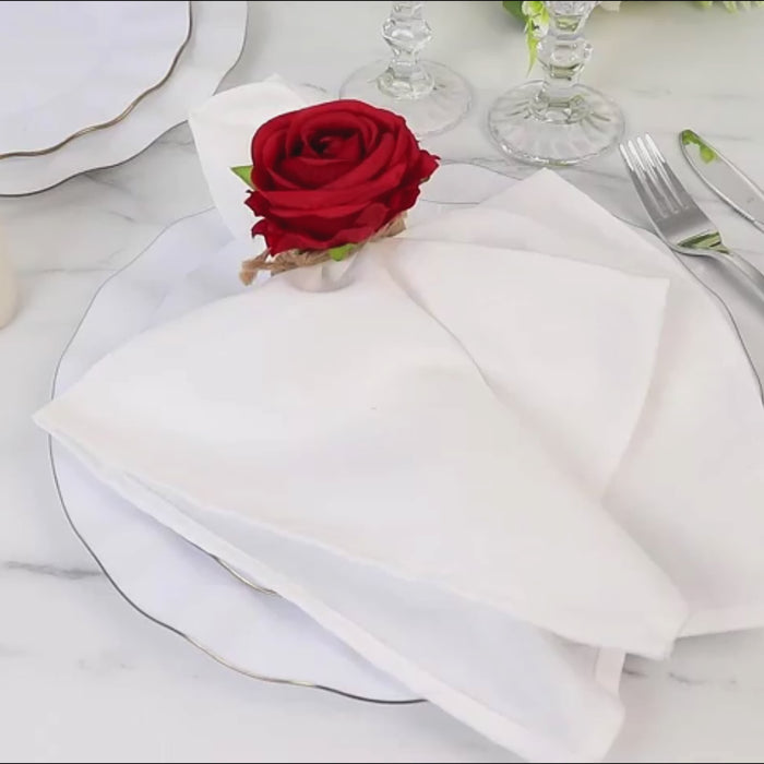 Red silk rose flower napkin ring on a white plate setting.