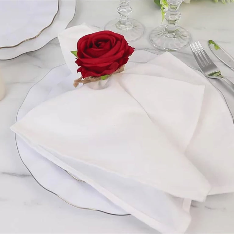 Red silk rose flower napkin ring on a white plate setting.