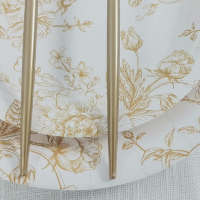 Gold plastic forks on a floral white plate, premium disposable dinner flatware.
