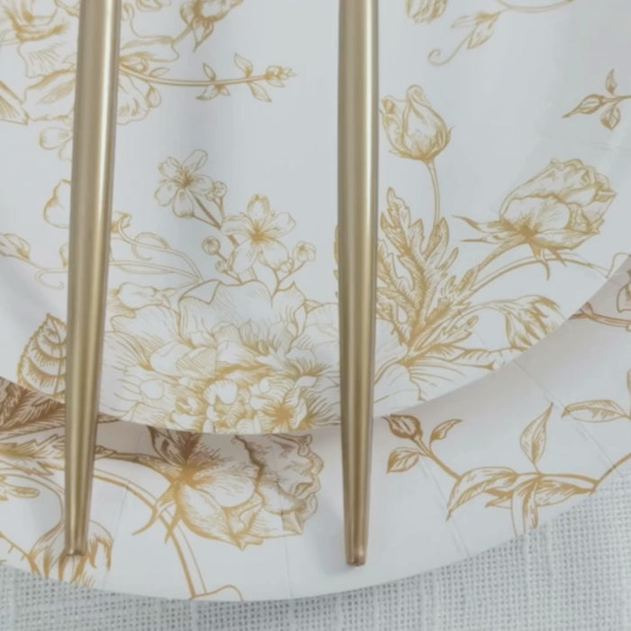 Gold plastic forks on a floral white plate, premium disposable dinner flatware.