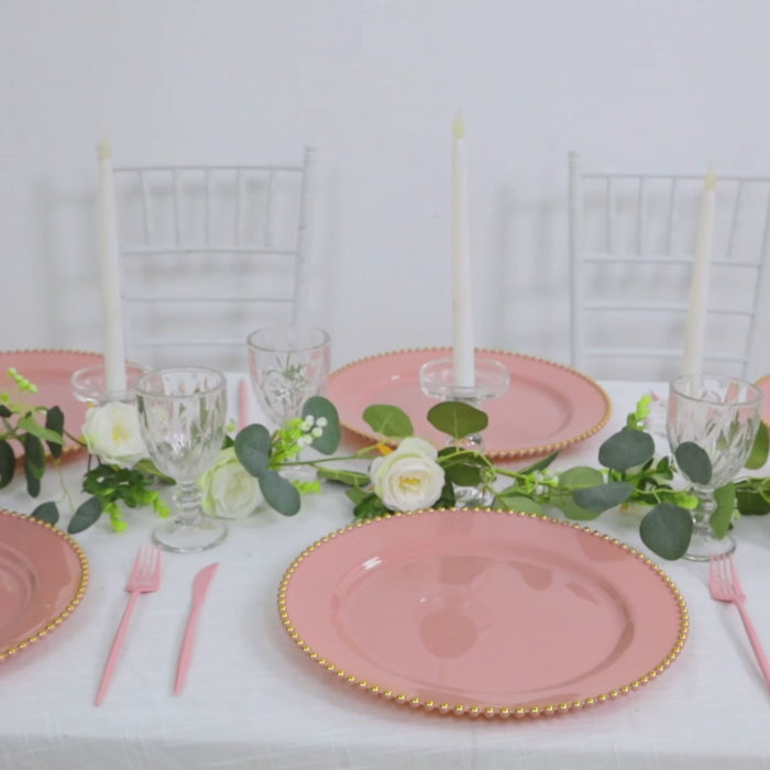 Dusty rose charger plates with gold beaded rim on a table setting.