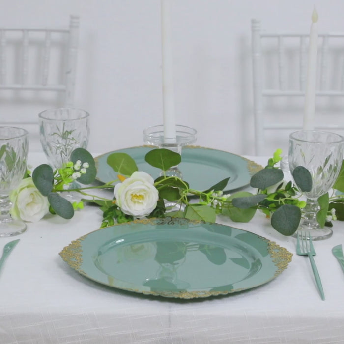 Dusty sage green charger plates with gold embossed rim on a dining table setting.
