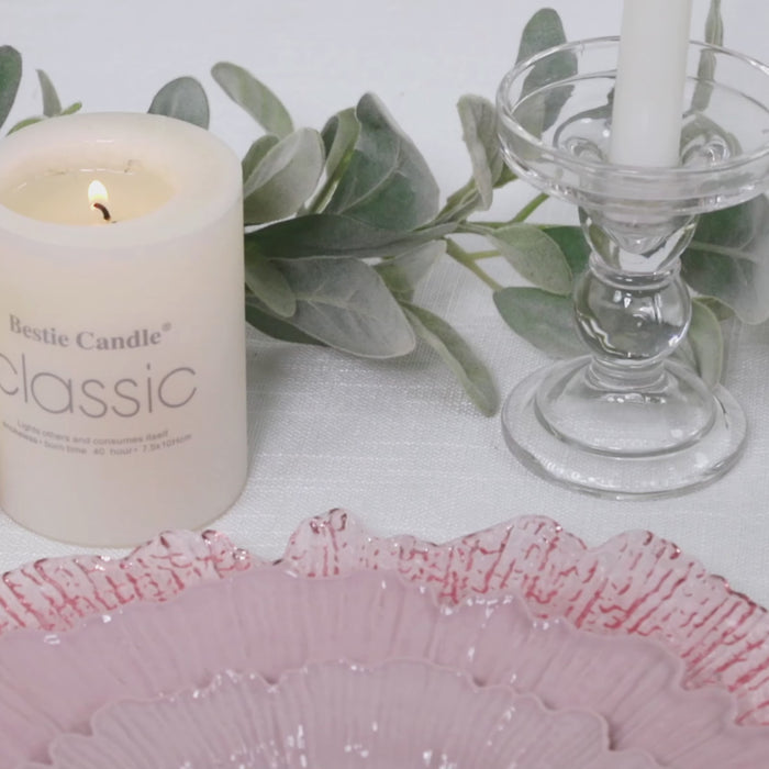 Blush plastic dessert and appetizer plates on a table setting with candle and greenery.