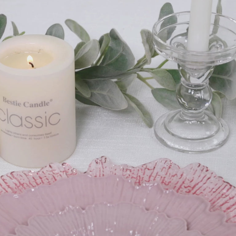 Blush plastic dessert and appetizer plates on a table setting with candle and greenery.