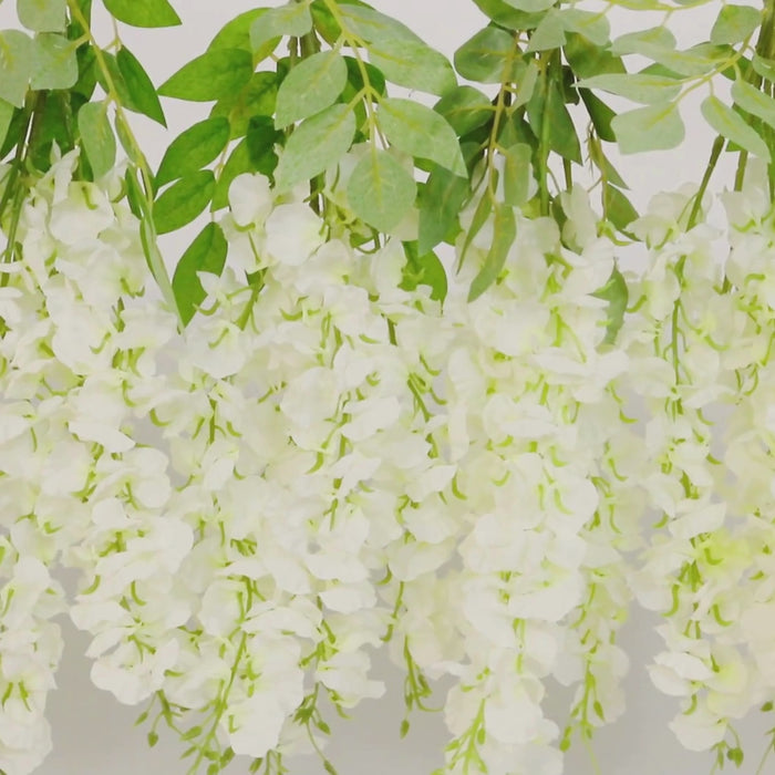 White artificial wisteria vines hanging plants with green leaves.