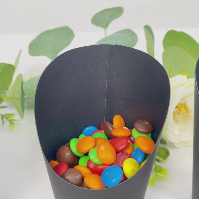 Black paper popcorn box filled with colorful snacks.