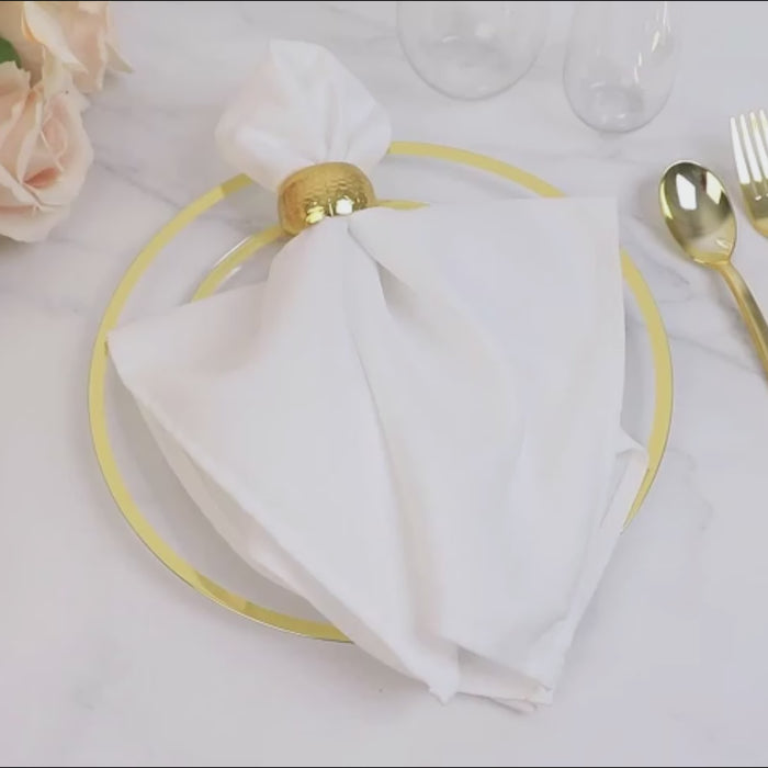 Clear plastic round dinner plate with gold rim on a table setting.