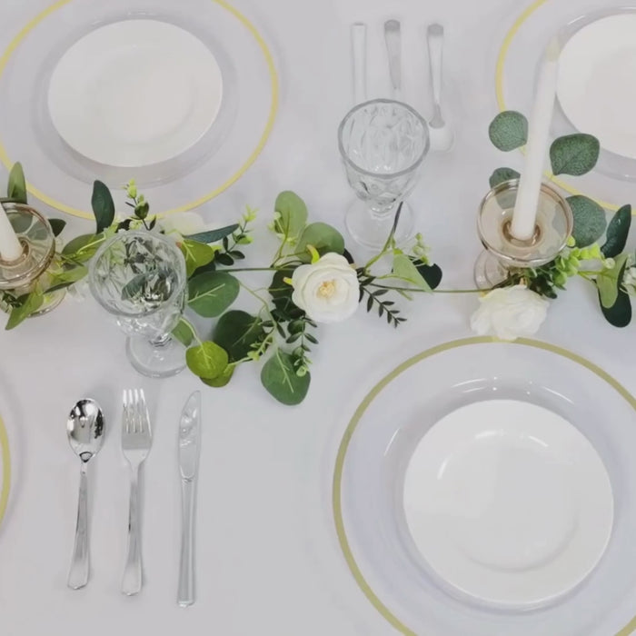 Clear charger plates with wide gold rim set on a table for a dinner party.
