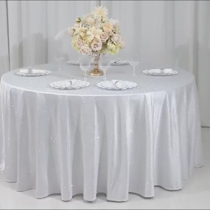 White tablecloth with rhinestone accents on a round table, elegantly set for an event.