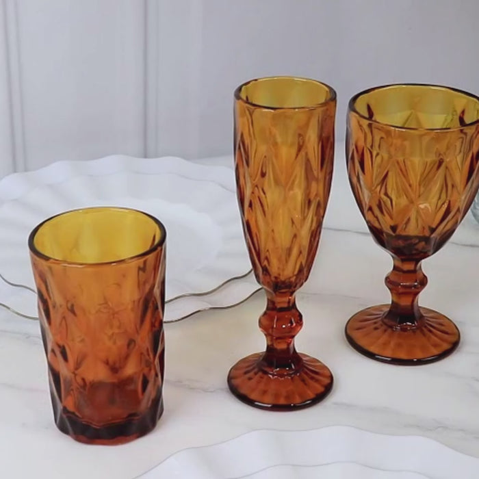 Amber gold textured whiskey glasses on a white marble surface.