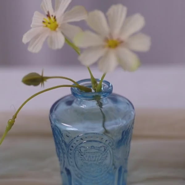 Set of 6 vintage embossed blue glass bud vases with white flowers.