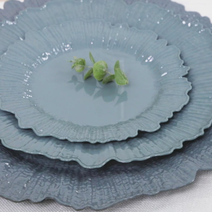 Dusty blue reef design plastic plates stacked with greenery.