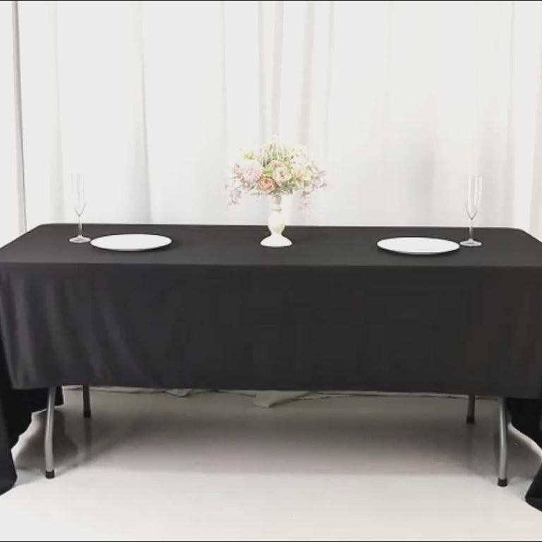 Black wrinkle-free tablecloth on a dining table with floral centerpiece.