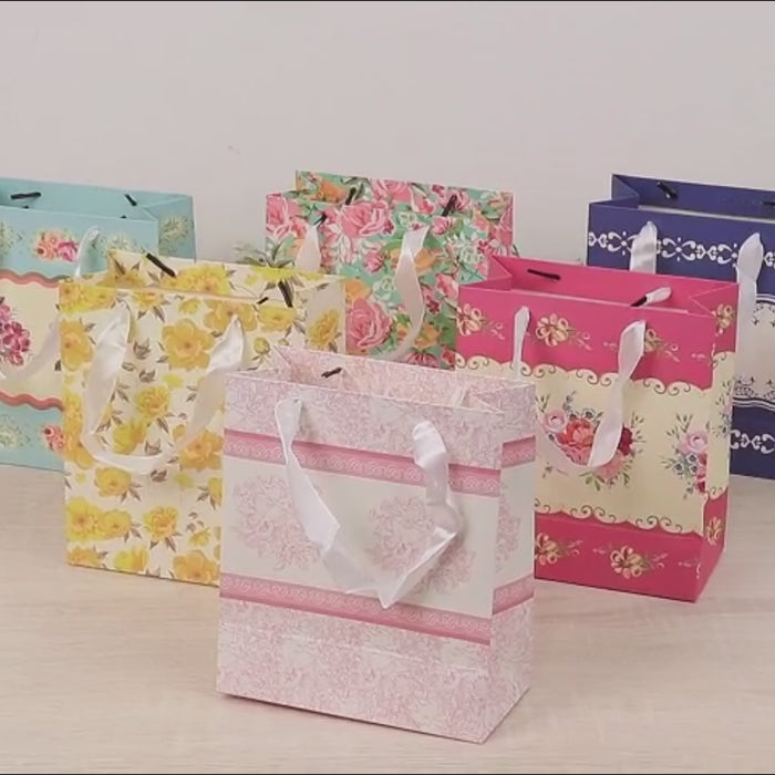 Mixed vintage floral gift bags with ribbon handles in assorted colors.