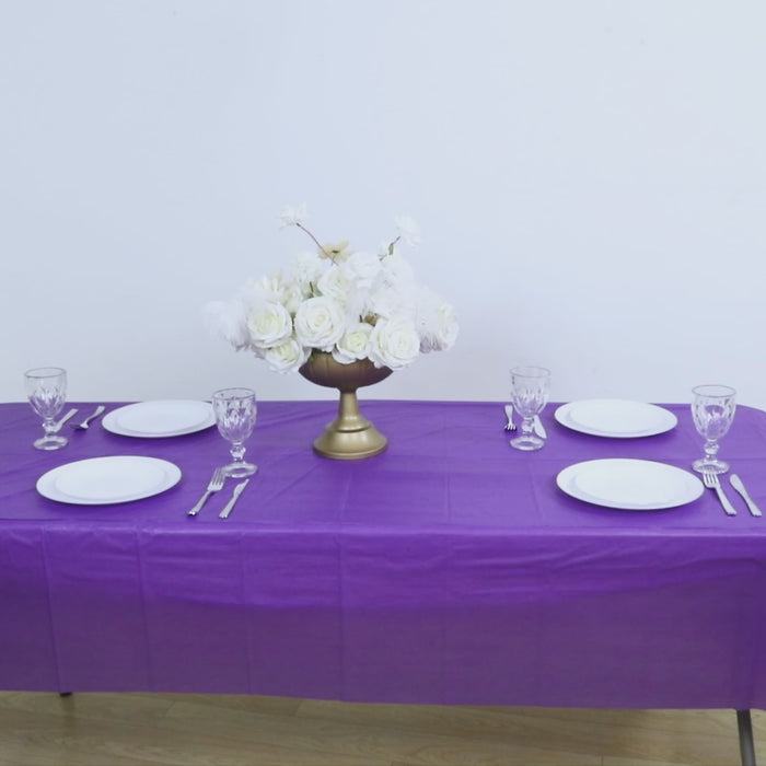 Purple disposable table cover with white floral centerpiece and table settings.
