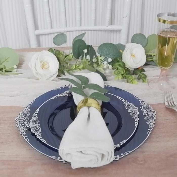 Navy blue plastic dessert plate with silver leaf embossed rim on a dining table setting.