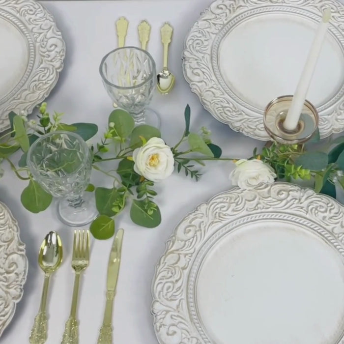 Antique white gold engraved charger plates with vintage decor on a table setting.
