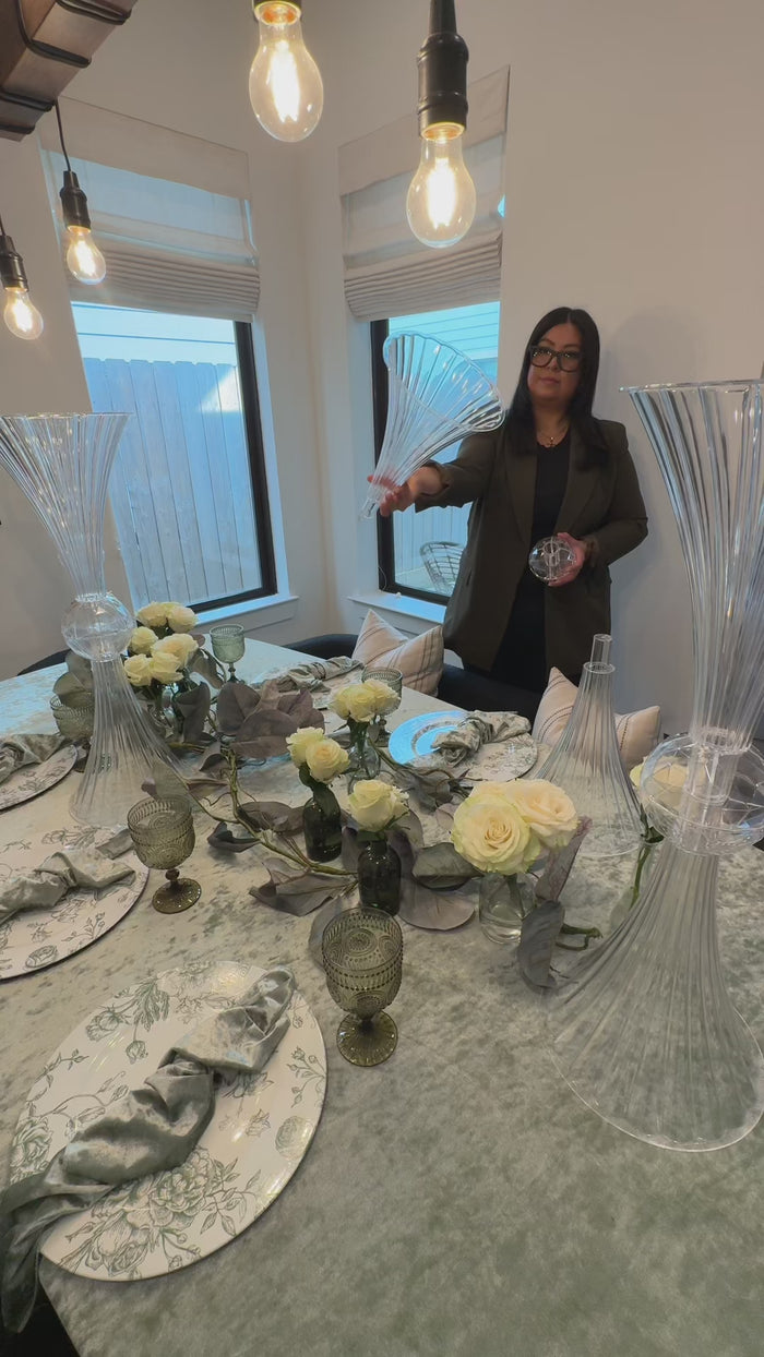 Clear ribbed acrylic trumpet vases with crystal ball accents on a dining table.