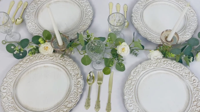 Antique white gold engraved charger plates with vintage decor on a table setting.