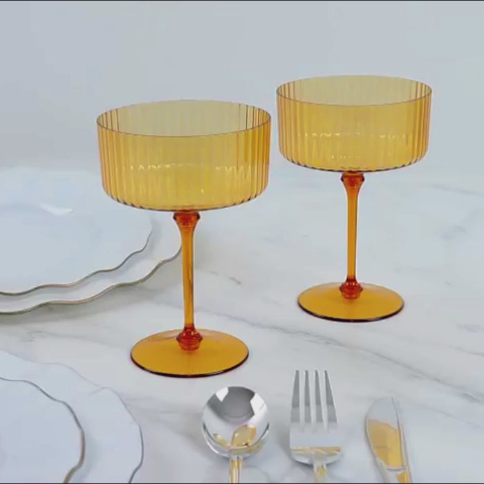 Amber gold disposable cocktail glasses on a marble surface.