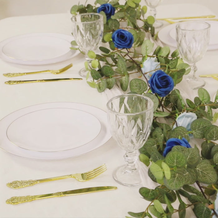Artificial eucalyptus garland with royal blue and light blue silk roses on a table setting.