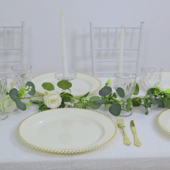 Ivory charger plates with gold beaded rim on a dining table setting.