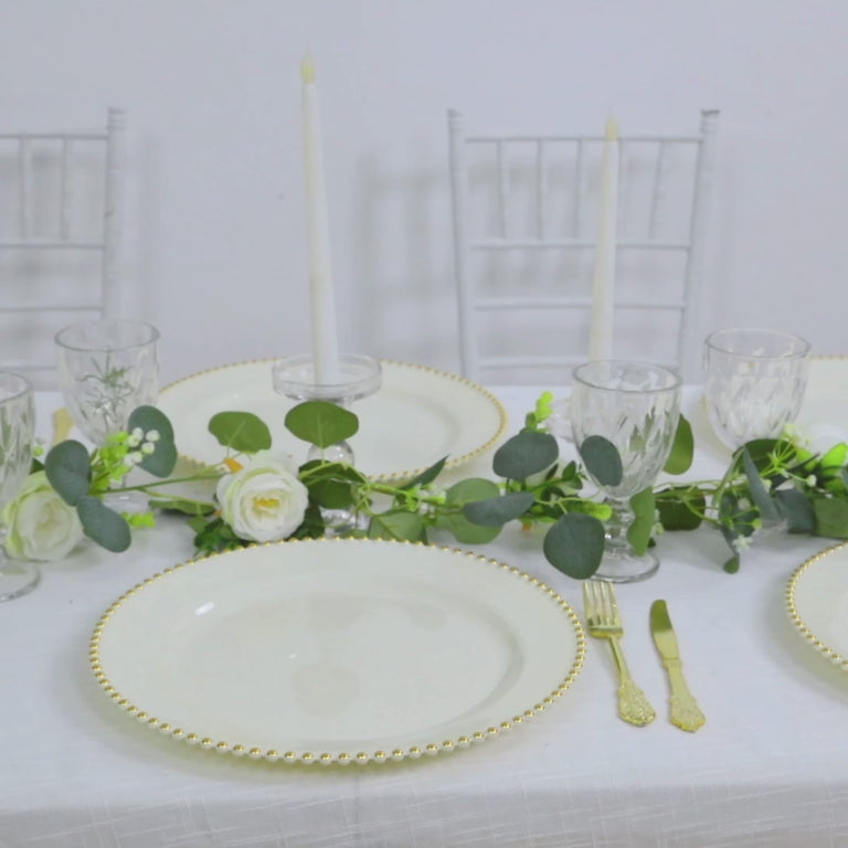 Ivory charger plates with gold beaded rim on a dining table setting.