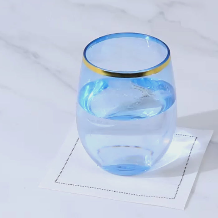 Dusty blue stemless wine glass with gold rim filled with water.