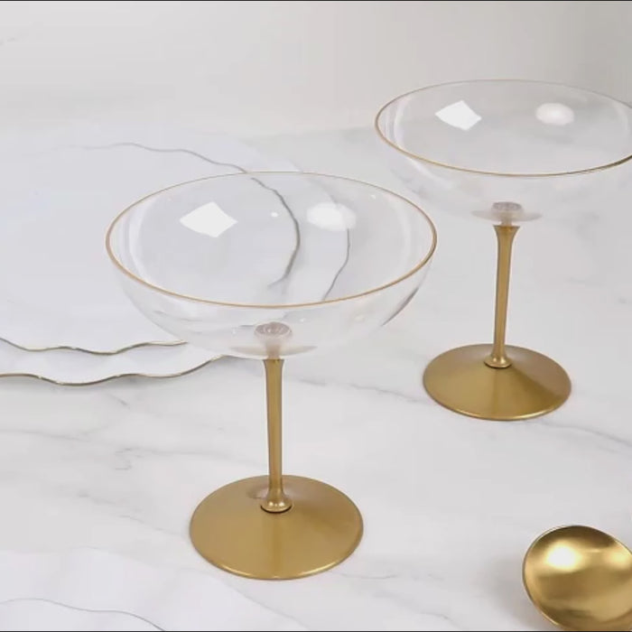 Clear plastic coupe champagne cups with gold stems.