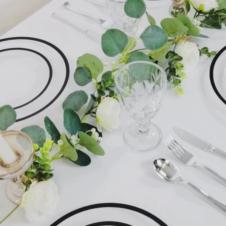 Clear charger plates with wide black rim on a dinner table setting.