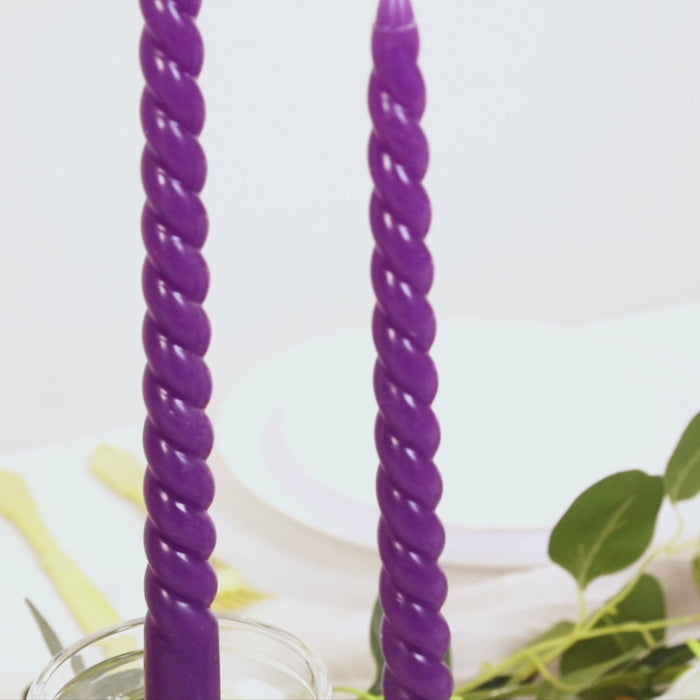 Purple spiral taper candles in a glass holder.