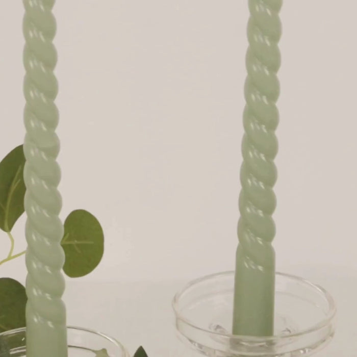 Sage green unscented spiral taper candles in decorative holders.
