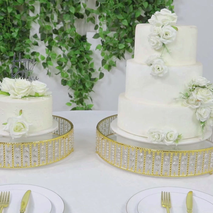 Gold crystal cake stand with hanging beads, displaying elegant white cakes.