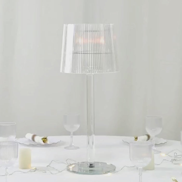 Clear acrylic candle lamp with ribbed shade on a table setting.