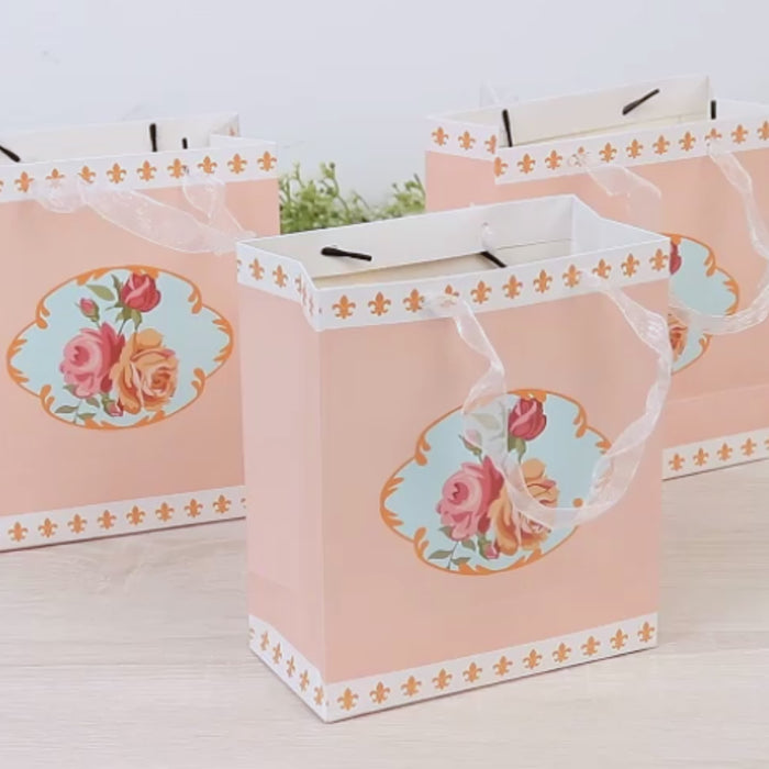Dusty rose floral gift bags with ribbon handles, perfect for tea parties.