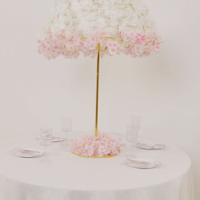 Gold floral umbrella stand centerpiece with pink flowers on a round table.