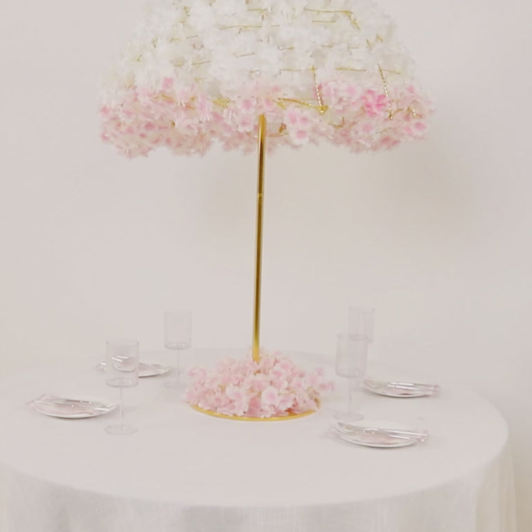 Gold floral umbrella stand centerpiece with pink flowers on a round table.
