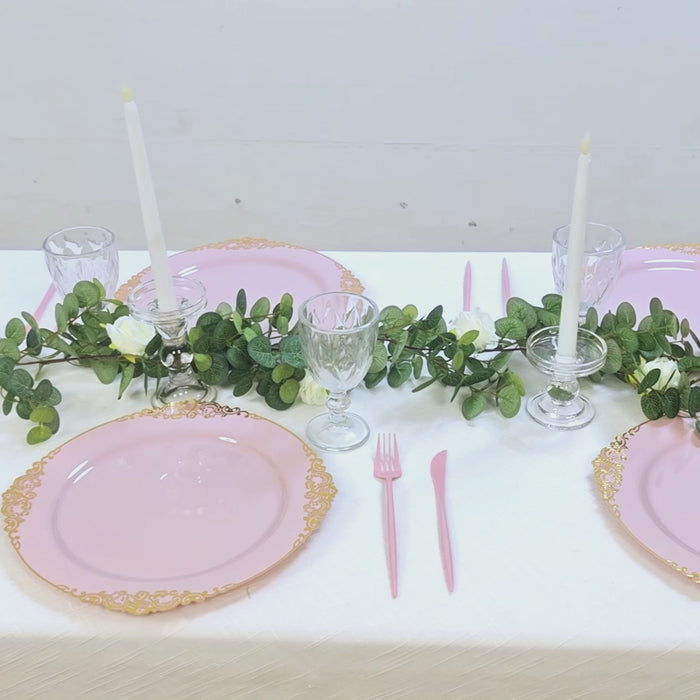 Blush pink charger plates with gold embossed rim on a dining table setting.