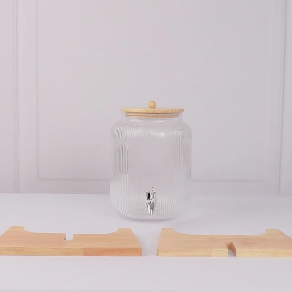 Clear glass beverage dispenser with wooden stand and lid.