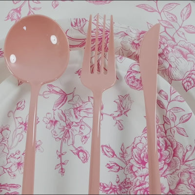 Dusty rose heavy-duty plastic utensils on a floral plate.