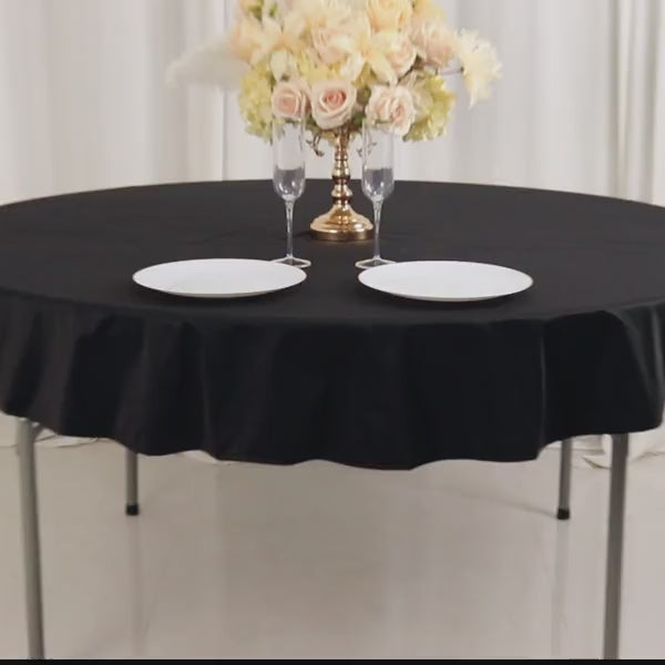 Black round tablecloth set with elegant tableware and floral centerpiece.
