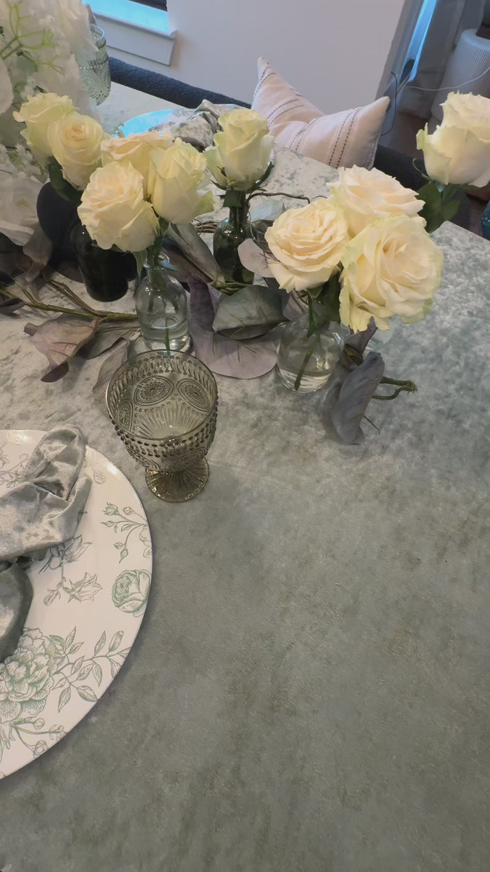White artificial rose floral centerpiece on a table setting.