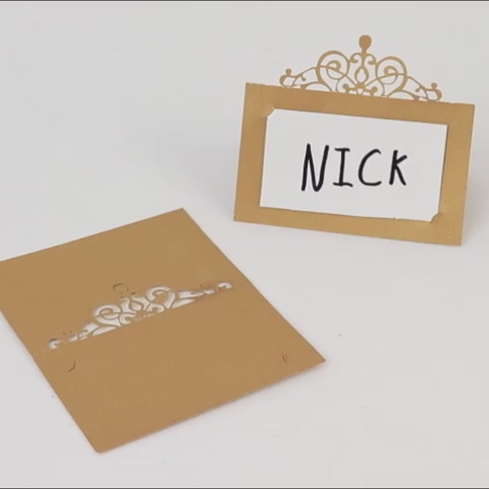 Gold laser cut place cards with crown design for seating arrangements.