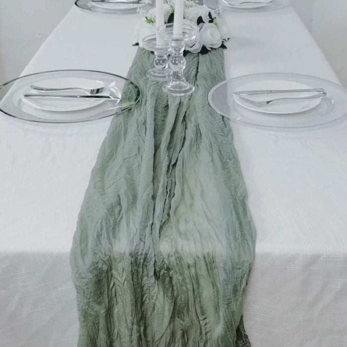 Dusty sage green gauze cheesecloth table runner on a white table setting.