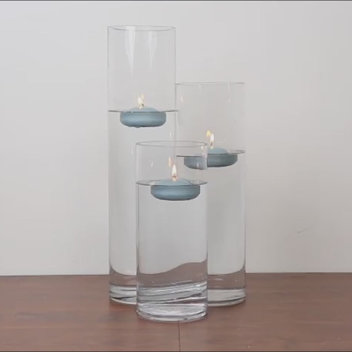 Silver floating candles in clear glass vases with water.