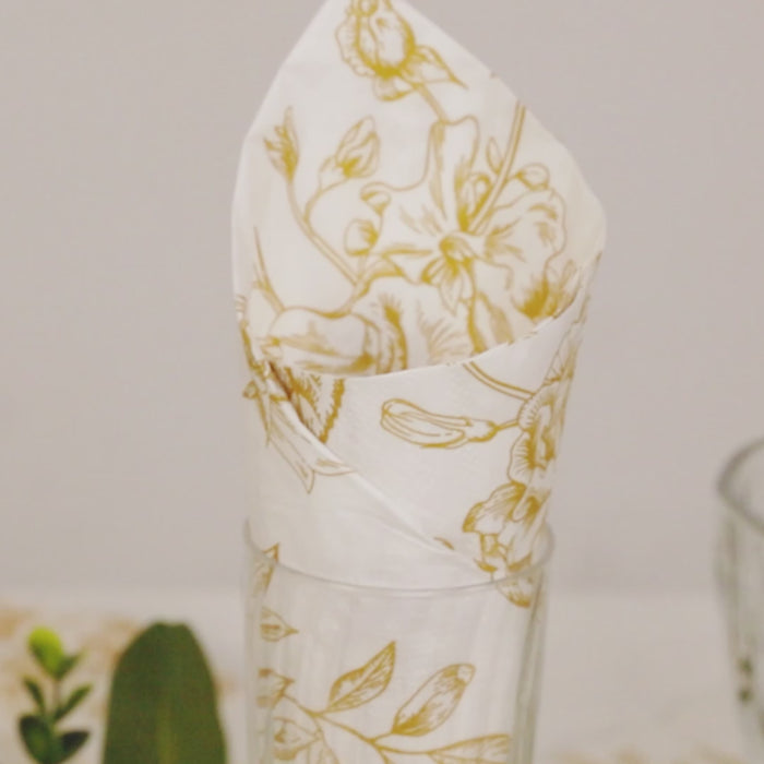 White napkins with gold French toile floral pattern in a glass.
