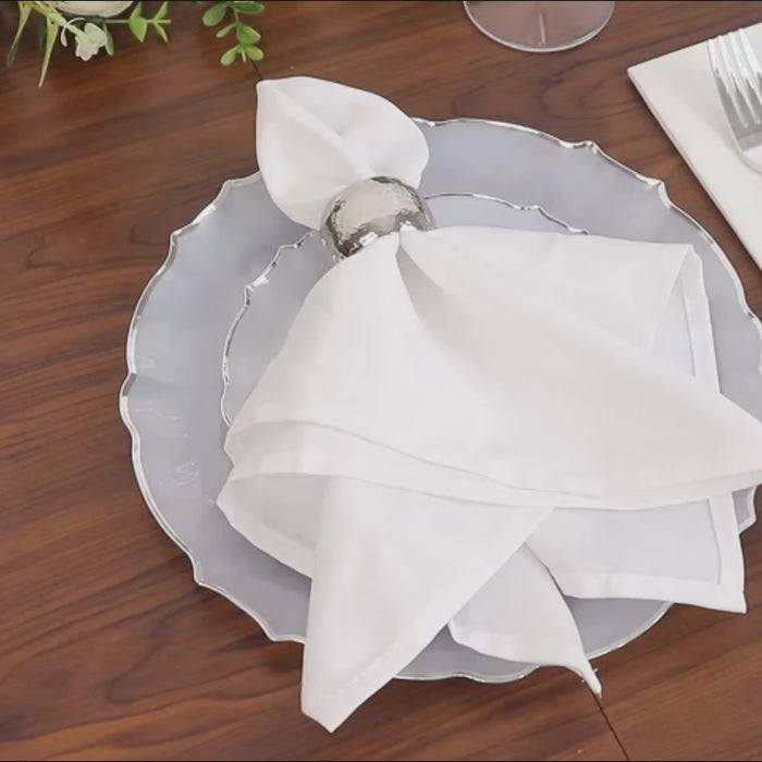 Pearl white round appetizer plate with silver scalloped rim on a wooden table.
