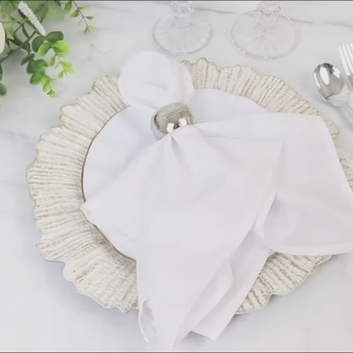 Antique white charger plate with reef design and white napkin setting.