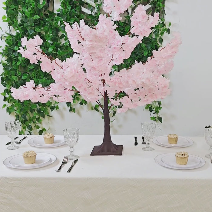 Blush pink artificial cherry blossom tree centerpiece on dining table.